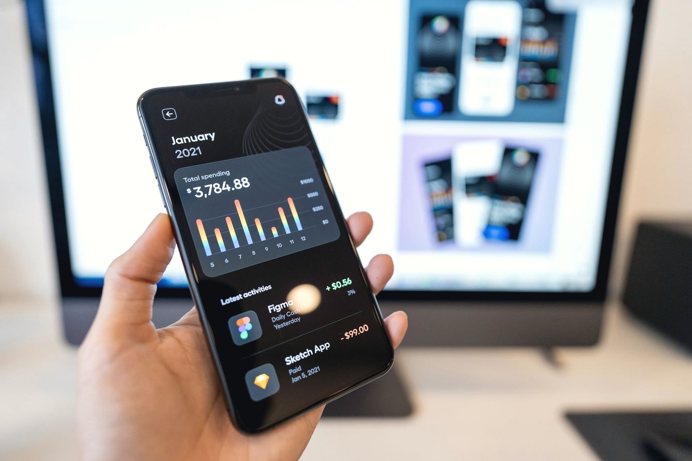 Mano sosteniendo un teléfono con un dashboard en modo oscuro